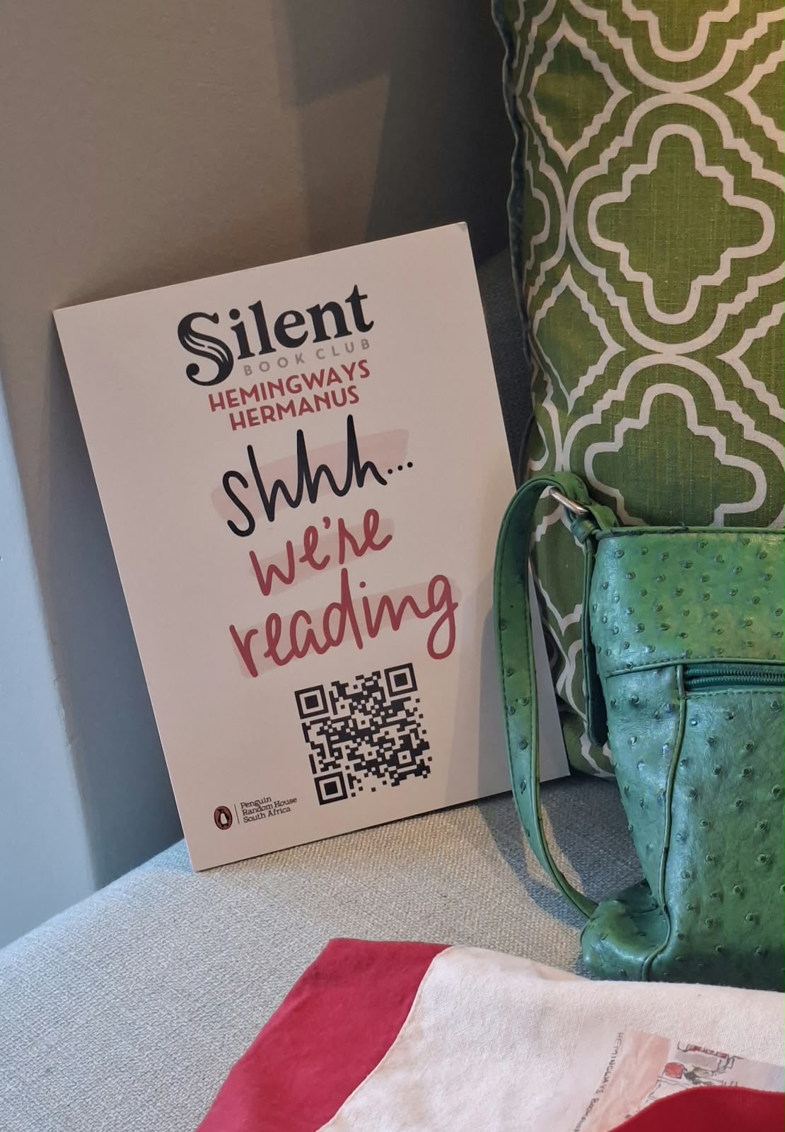 Hemingways Silent Book Club sign beside a book and a green bag